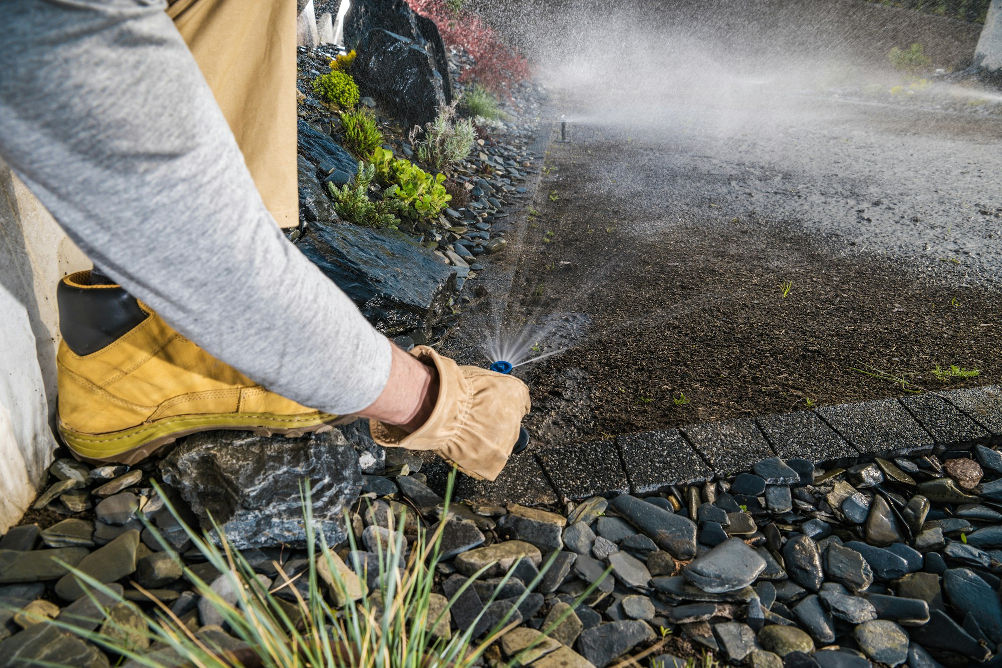 Landscaping Worker Adjusting Garden Water Sprinkler